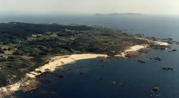 Vista aérea de la playa de Barreiro o Grove, con arena dorada, rocas y el mar azul.