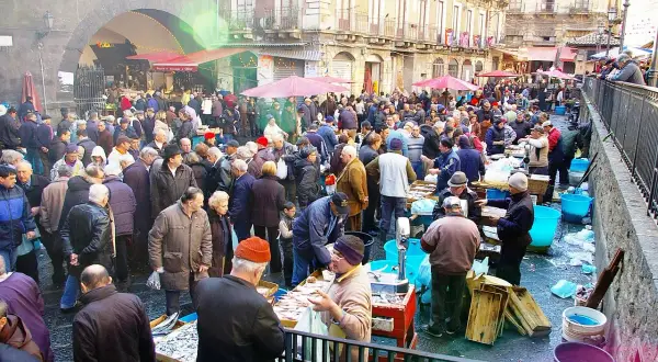 Mercado bullicioso en Palermo, con gente comprando pescado fresco. Un día ajetreado en este lugar, que algunos consideran **palermo peligroso** por su intensidad.