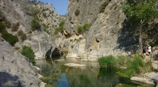 Un cañón con un río de aguas cristalinas y vegetación exuberante, ideal para disfrutar de los warmwaterbronnen in Spanje.
