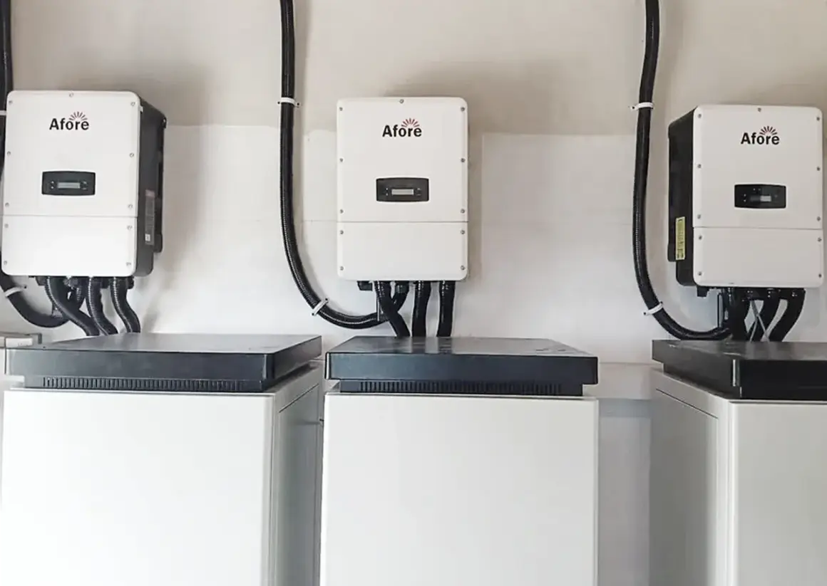 Tres inversores solares Afore, blancos y rectangulares, montados en pared, conectados a unidades inferiores.