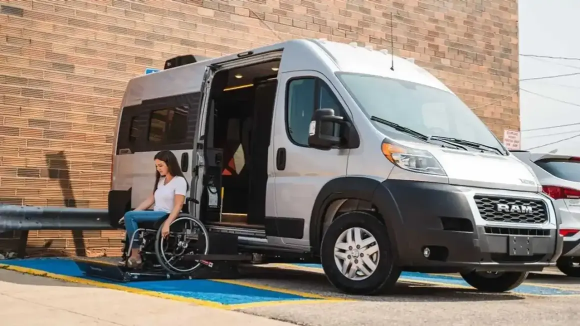 Mujer en silla de ruedas desciende de un minibus vivienda con rampa accesible.
