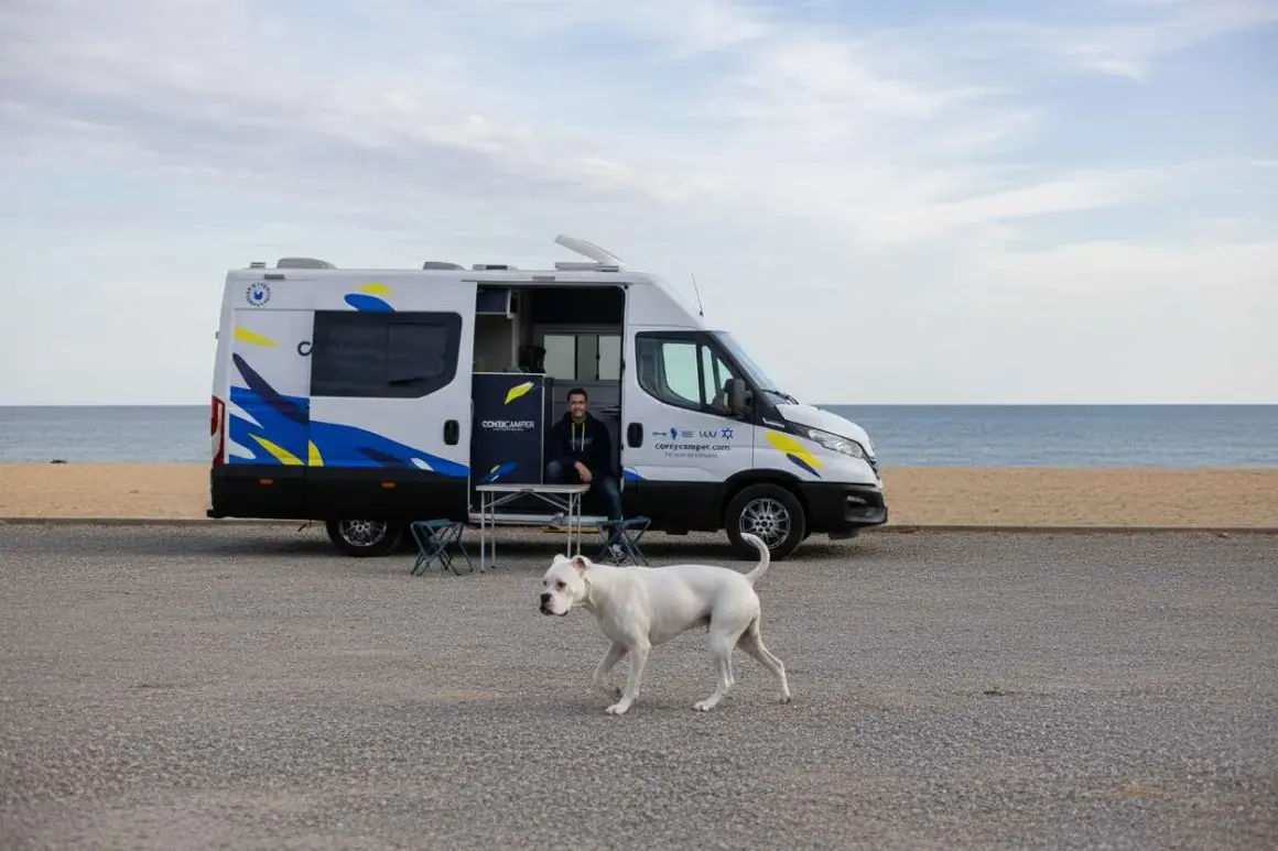 Un hombre y su perro blanco disfrutan de un día en la playa cerca de un pueblo teba.