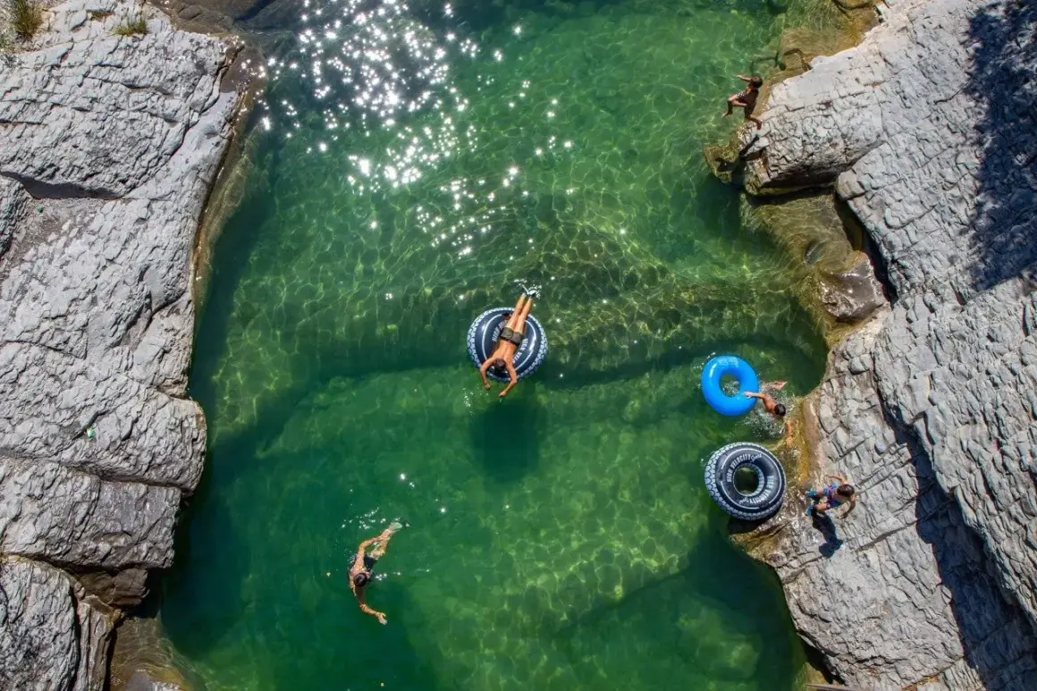 Disfrutando de las pozas cerca de Ainsa. Niños nadan y flotan en aguas cristalinas rodeadas de rocas.