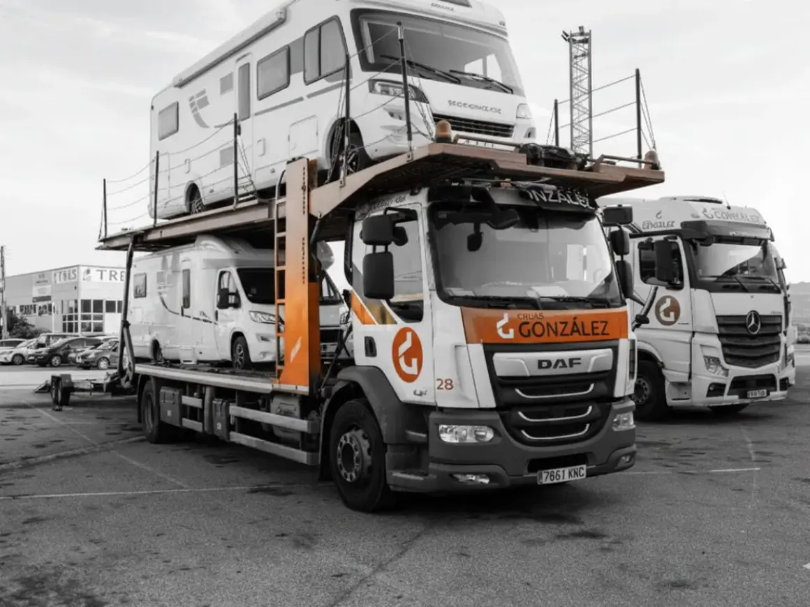 Camión transportando caravanas, dos vehículos recreativos apilados listos para su transporte.