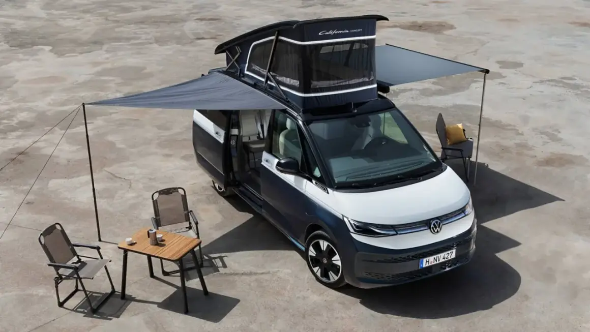 La vw california electrica lista para la aventura, con toldo extendido, mesa y sillas, lista para disfrutar del aire libre.