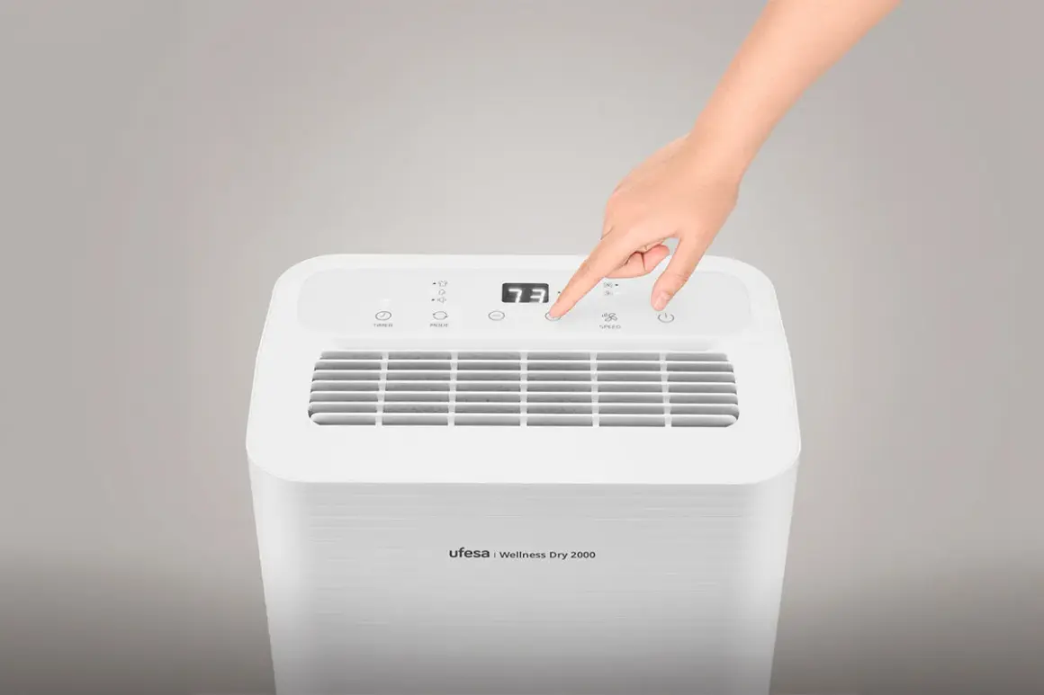 Mano ajustando la velocidad de un deshumidificador Ufesa Wellness Dry 2000. ¡No gasta mucho!