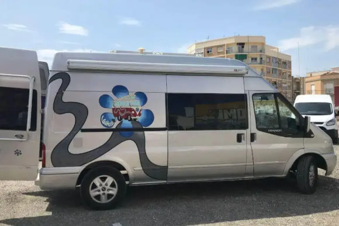 Furgoneta camperizada con motor Ford 2.2 TDCI 140 CV. Decoración de flor azul y carretera gris.