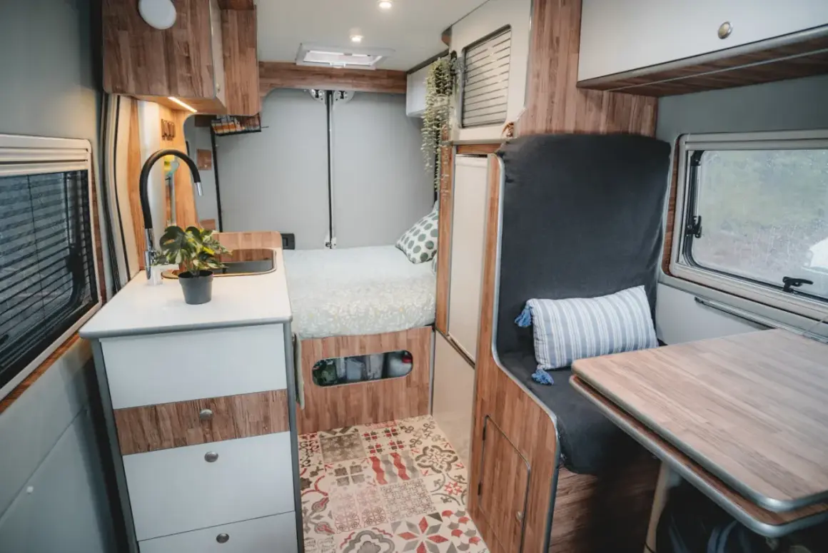 Interior de camper con cama, cocina y zona de asientos. ¡Ideas camper para tu próxima aventura!