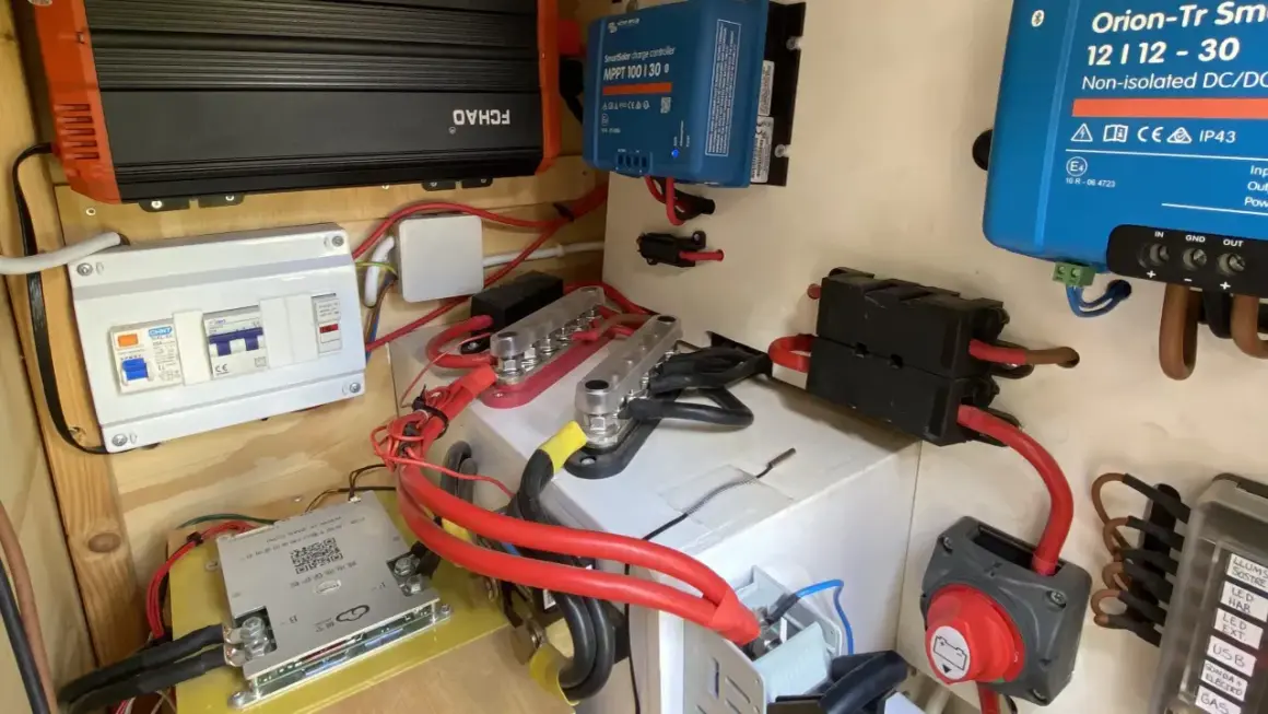 Sistema eléctrico con varios componentes, incluyendo un inversor, regulador solar y disyuntores. El grosor del cable eléctrico es notable en las conexiones principales.