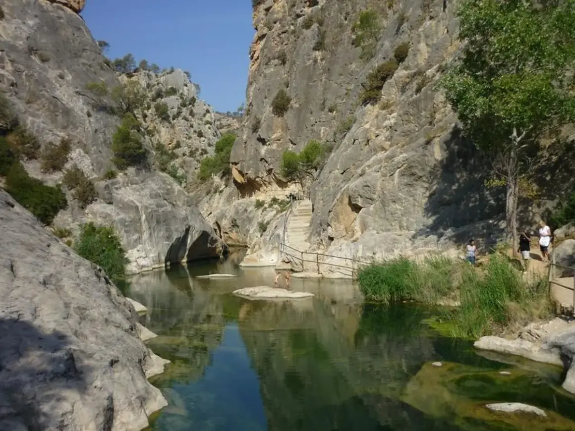 Un cañón con un río de aguas cristalinas y vegetación exuberante, ideal para disfrutar de los warmwaterbronnen in Spanje.