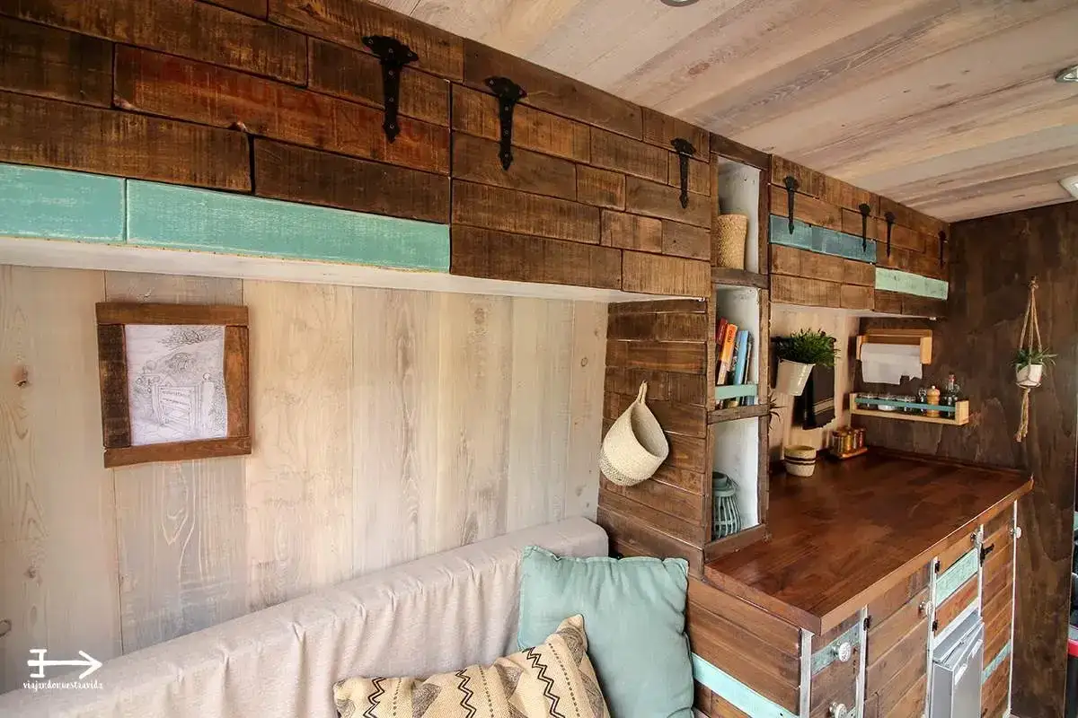 Detalles de fabricantes de muebles para caravanas: un sof&aacute;, encimera de madera, estanter&iacute;as y decoraci&oacute;n r&uacute;stica.