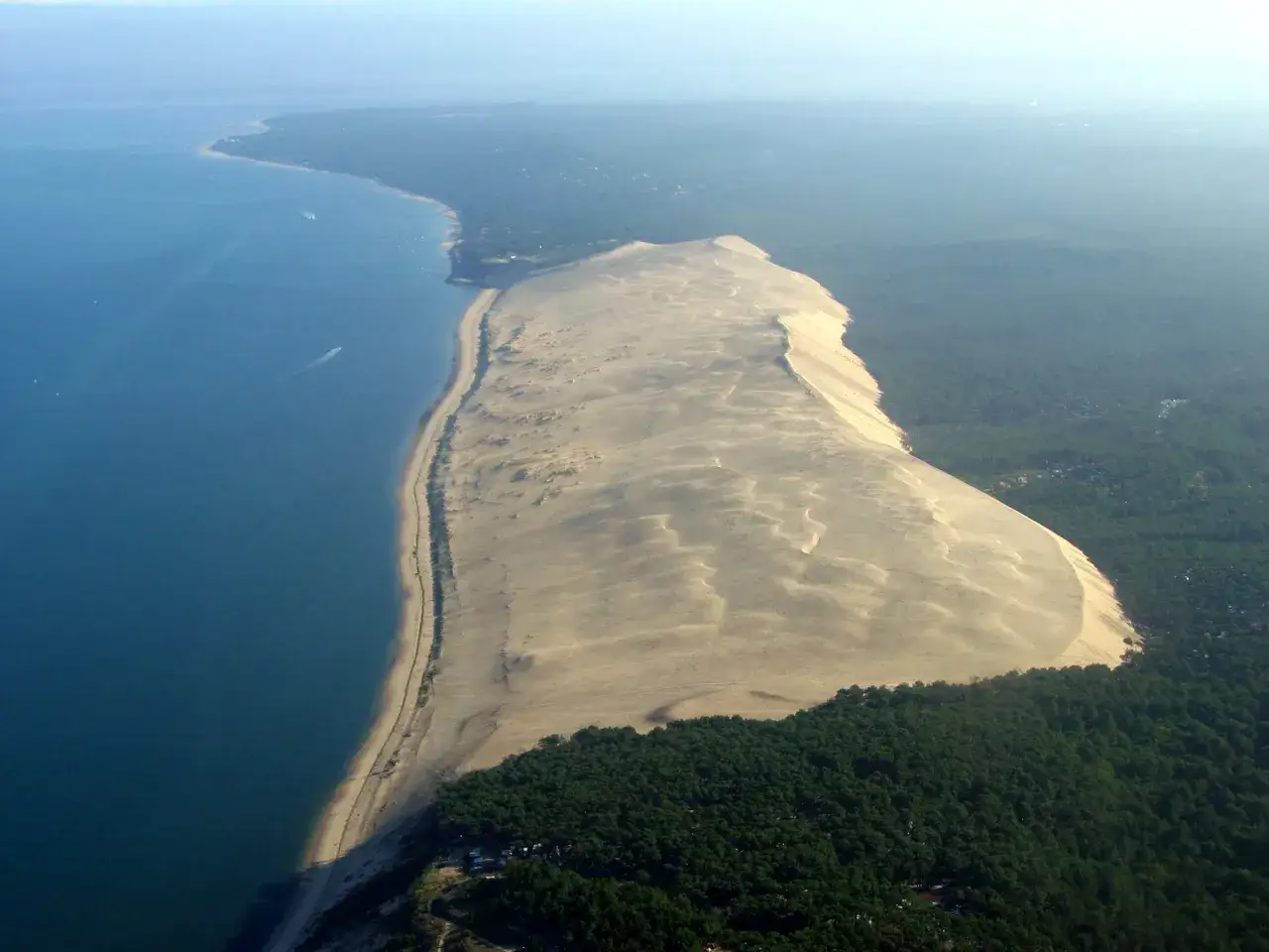 Vista a&eacute;rea de la duna de Pilat, la duna m&aacute;s alta de Europa, en Las Landas, Francia. El mar azul contrasta con la arena dorada y el verde de los pinos.