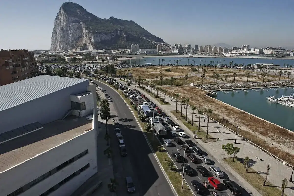 Larga cola de coches para visitar Gibraltar. El Pe&ntilde;&oacute;n domina el paisaje, con la ciudad y el puerto deportivo al fondo.