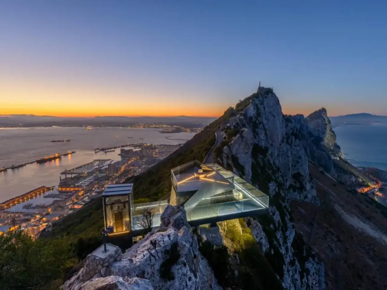 Atardecer sobre el Pe&ntilde;&oacute;n de Gibraltar, con el Skywalk iluminado y la ciudad extendi&eacute;ndose hacia el mar.