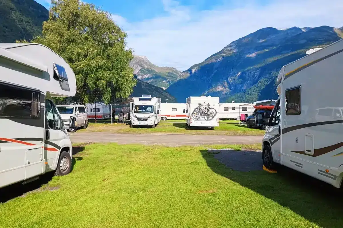 Autocaravanas low cost aparcadas en un camping con monta&ntilde;as al fondo. Unas vacaciones econ&oacute;micas y en plena naturaleza.