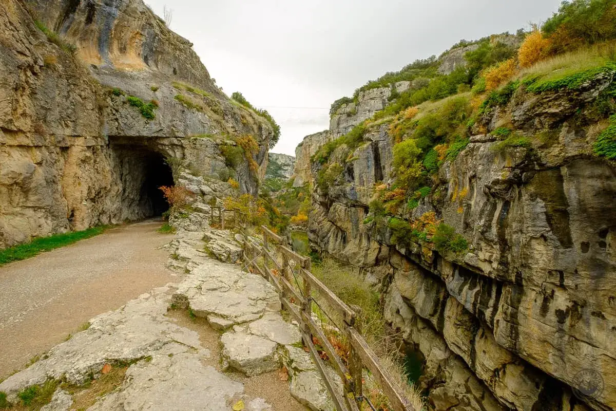 Sendero que se adentra en la foz de Lumbier, con un t&uacute;nel a la izquierda y un barranco a la derecha.