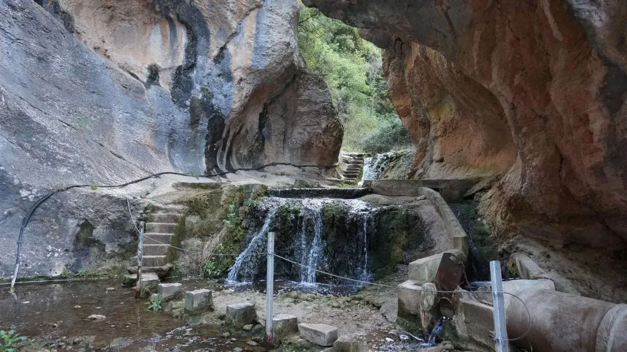 Cascada y escaleras en el congost de Baldellou, rodeado de rocas y vegetaci&oacute;n.
