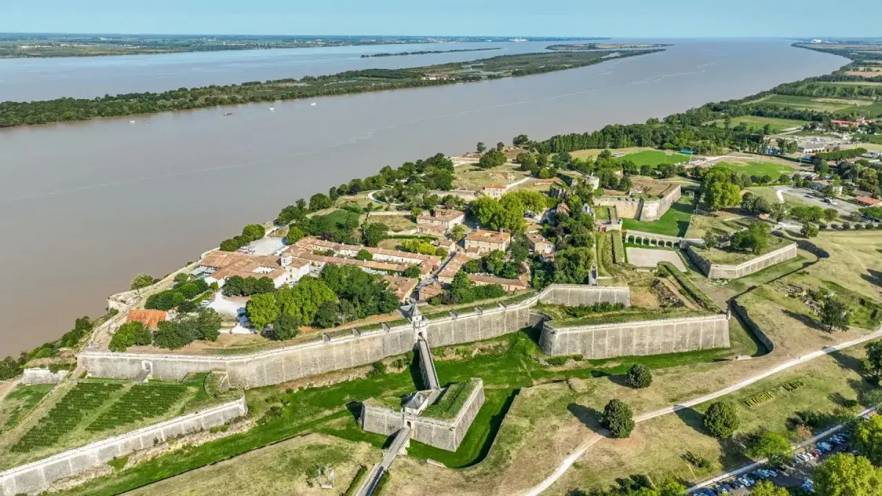 Vista a&eacute;rea de la ciudadela de Blaye, con sus imponentes murallas y edificios hist&oacute;ricos junto a un ancho r&iacute;o.