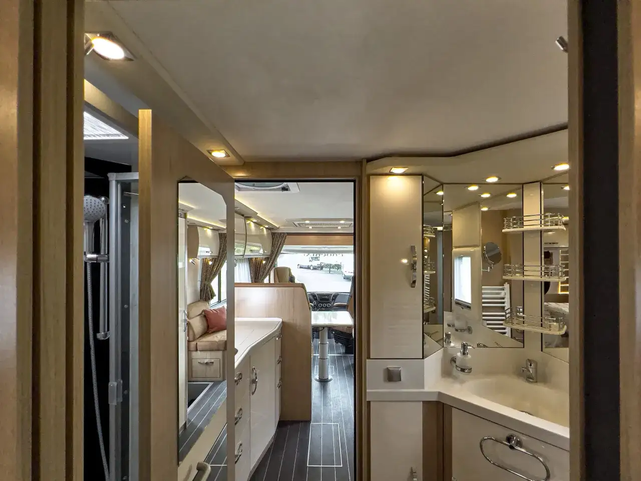 Interior de un autobús motorhome con ducha, lavabo y zona de comedor.
