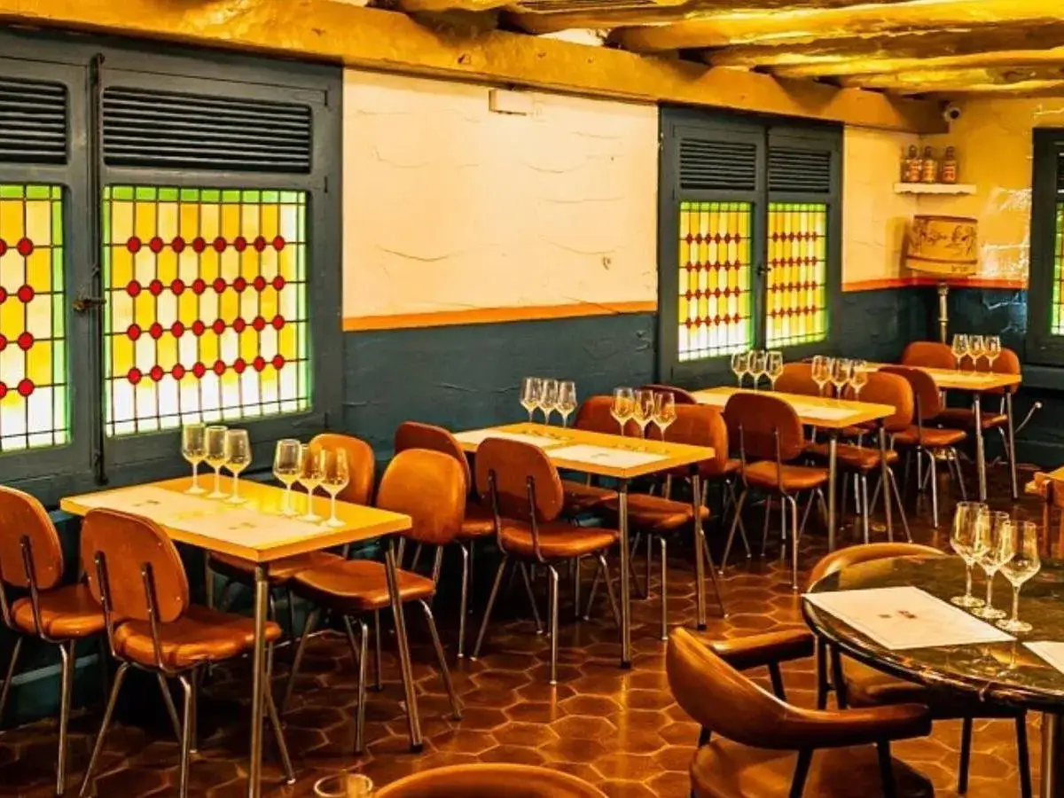 Mesas listas para disfrutar donde comer bien en Jaca. Ambiente acogedor con vidrieras de colores y sillas de cuero.