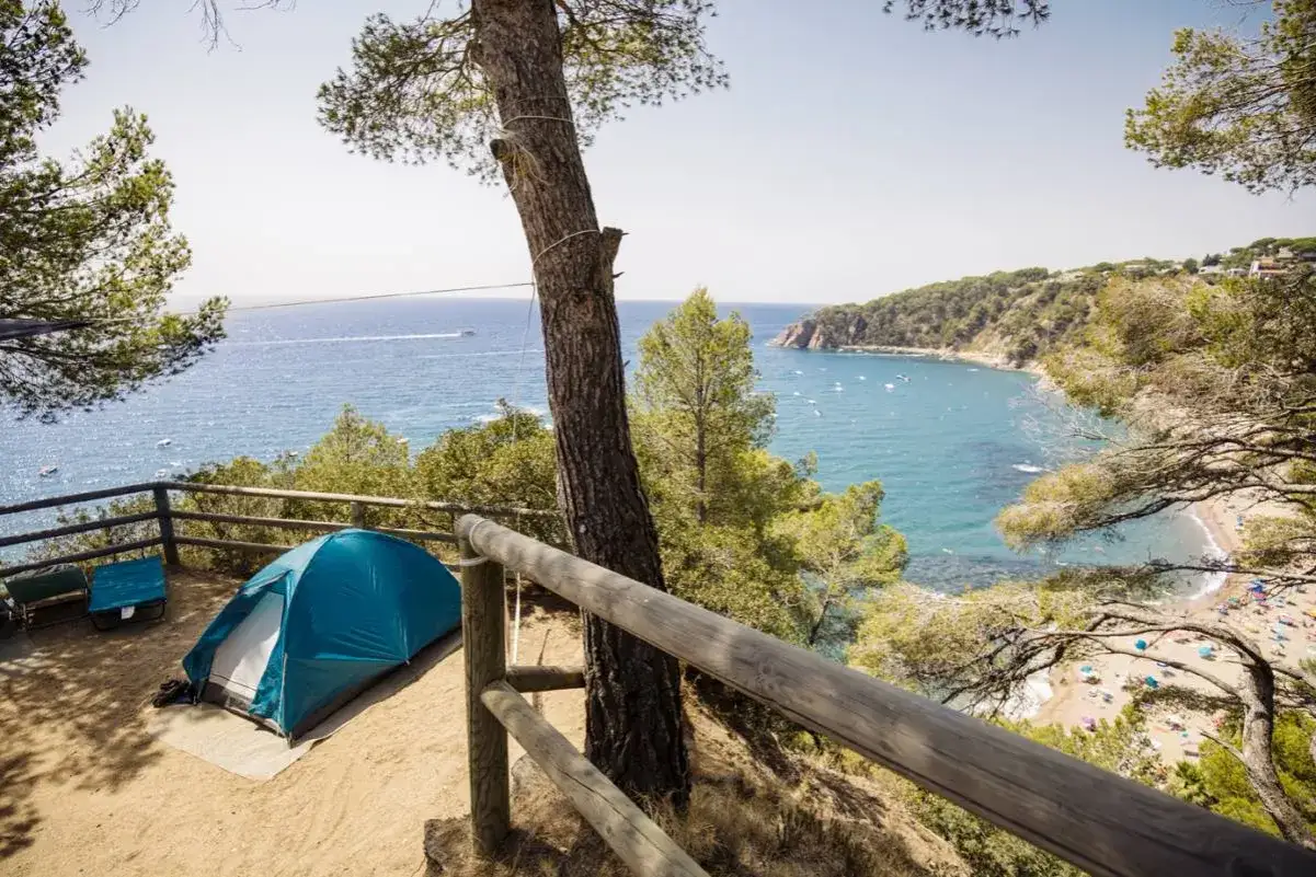 Acampada con tienda azul en la playa de las covaticas, con vistas al mar y a la bah&iacute;a.