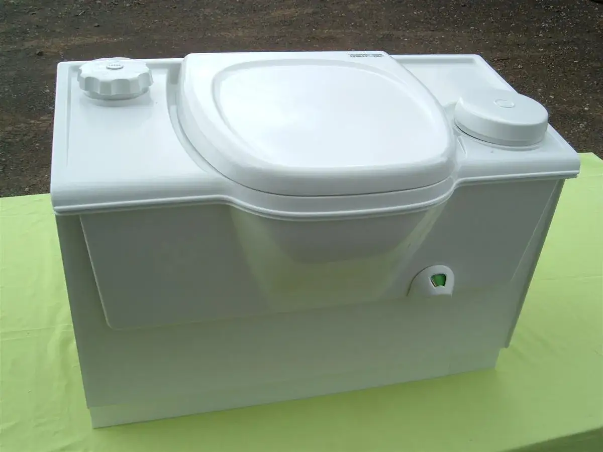 Inodoro port&aacute;til blanco con tapa y dos dep&oacute;sitos. Aqu&iacute; se explica como funciona un poti para viajes.