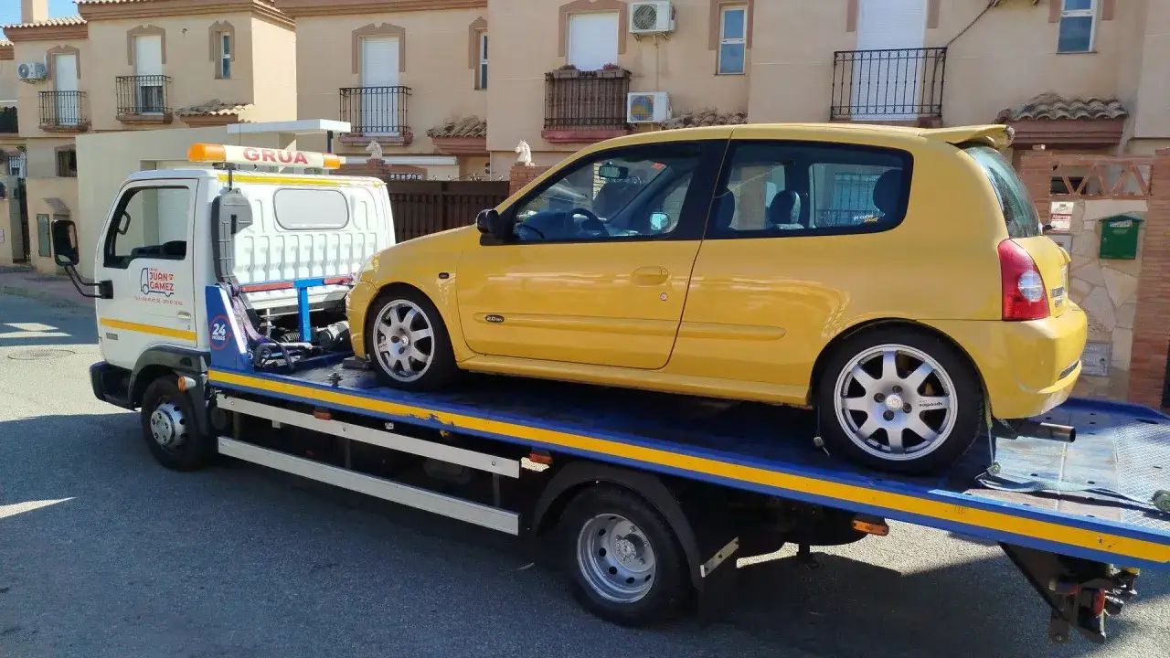 Gr&uacute;a transportando un coche amarillo deportivo. El veh&iacute;culo est&aacute; sobre la plataforma de la gr&uacute;a, listo para transportar.