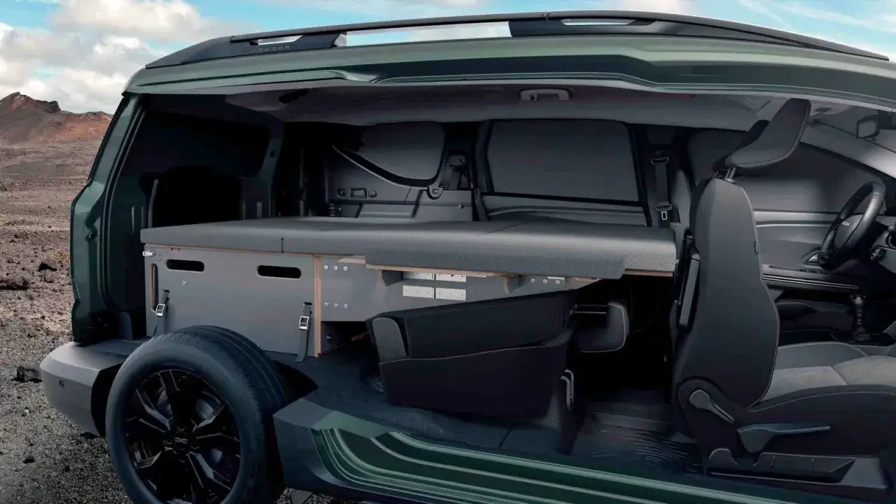Interior de una Dacia camper con cama y almacenamiento, lista para aventuras.