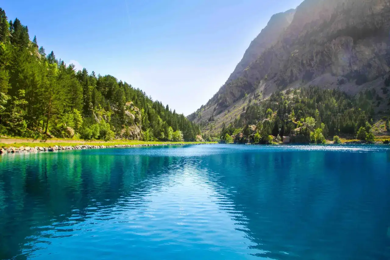 Lago azul turquesa rodeado de monta&ntilde;as y pinos, ideal para rutas desde Ba&ntilde;os de Panticosa.