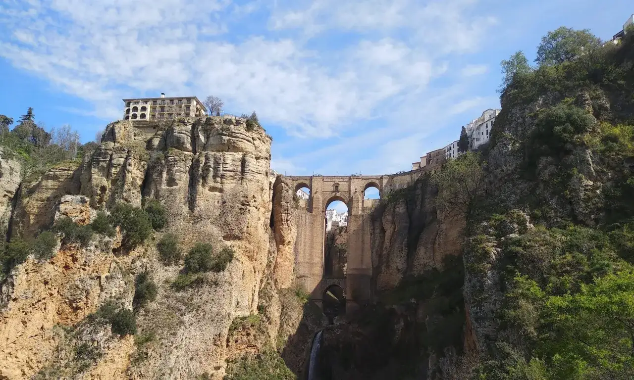 Un d&iacute;a soleado en Ronda, con el Puente Nuevo dominando el paisaje. Casas blancas se asoman entre los riscos.