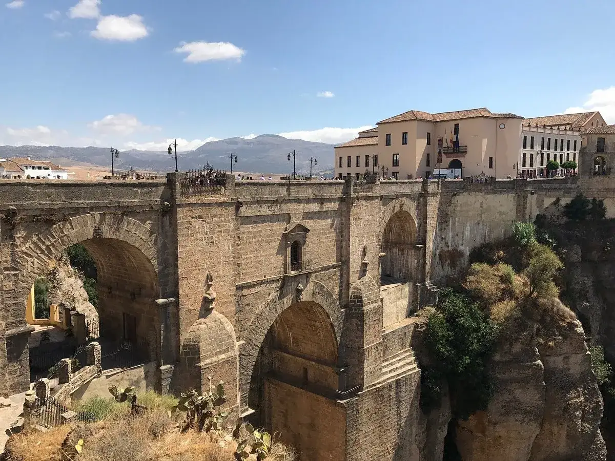 Puente Nuevo de Ronda, conectando la altstadt sobre un profundo desfiladero. Edificios históricos y montañas al fondo.