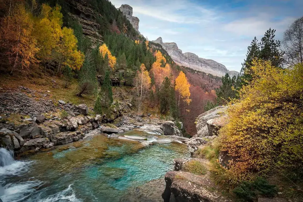 Cascada y pozas de aguas cristalinas en el Pirineo Aragon&eacute;s, rodeadas de bosques oto&ntilde;ales y imponentes monta&ntilde;as. Un lugar id&iacute;lico para disfrutar de las zonas de ba&ntilde;o.