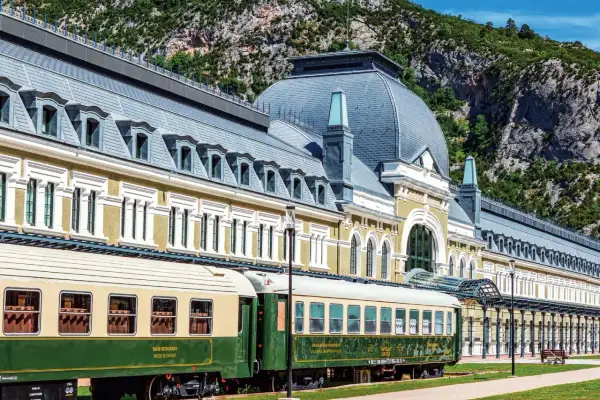 Estación de Canfranc, un lugar ideal donde comer bien en Jaca. Trenes clásicos esperan ante el imponente edificio.