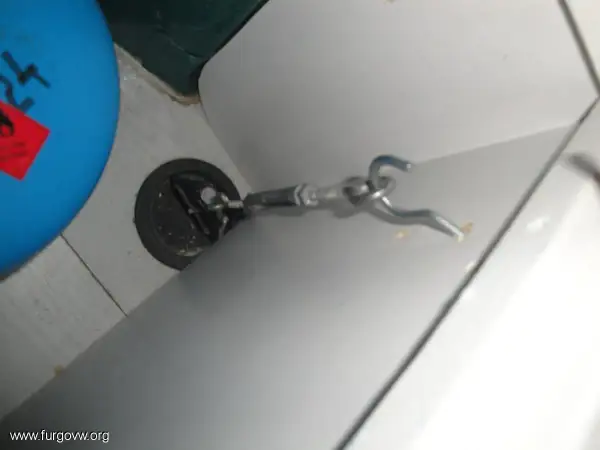 Detalle de cómo anclar muebles camper: un gancho metálico sujeto a un punto de anclaje en la pared de una autocaravana.