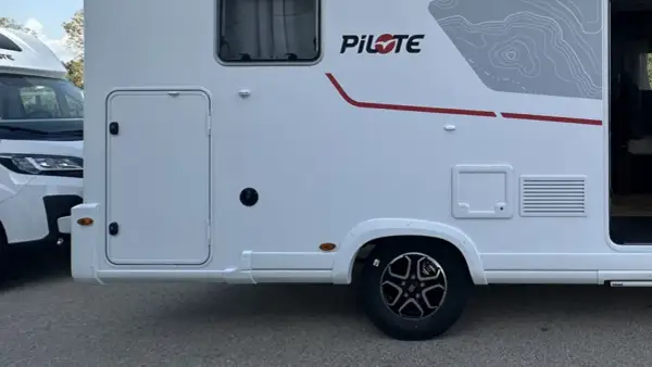 Autocaravanas con garaje, listas para la aventura. Detalle lateral de una autocaravana blanca con puerta de acceso y detalles gráficos.