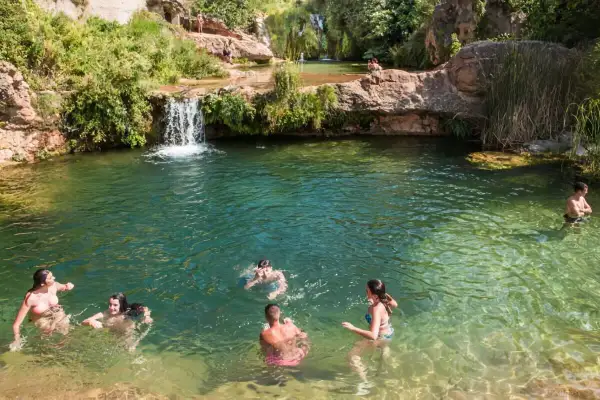 Gente disfrutando de las pozas cerca de Torla, con cascadas y vegetación exuberante.
