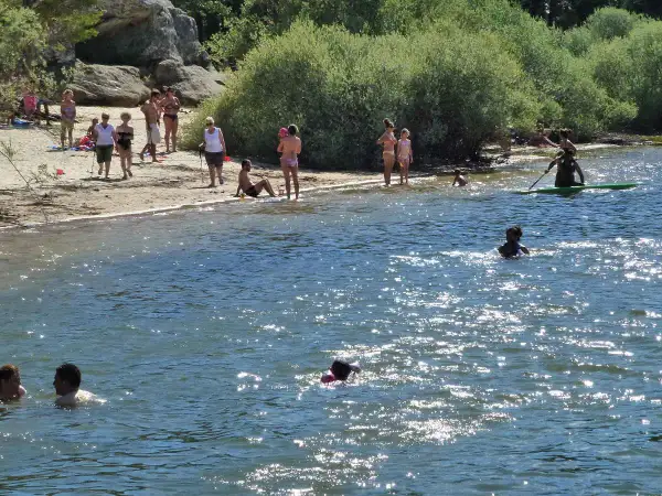 Gente disfrutando en la playa y el agua. Para llegar a esta playa, pita el camino.