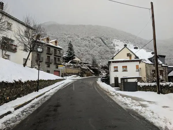 Un pueblo nevado, ideal para un fin de semana en Jaca. Casas de piedra y tejados blancos bajo un cielo gris.