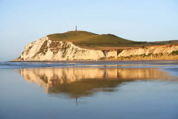 Acantilados blancos y verdes en Cap Blanc Nez, reflejados en el mar tranquilo.