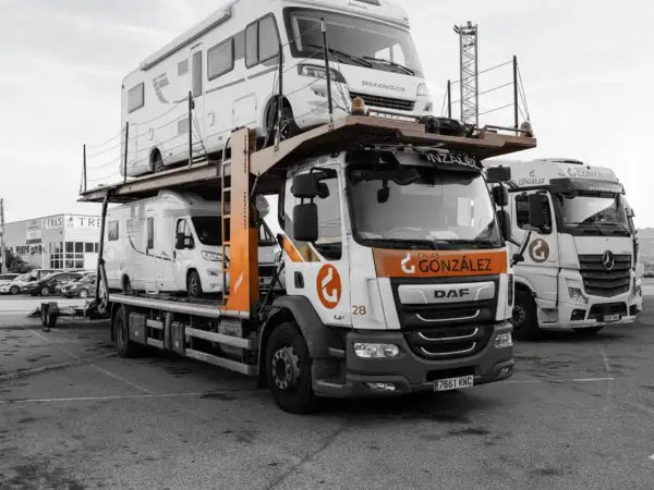 Camión transportando caravanas, dos vehículos recreativos apilados listos para su transporte.
