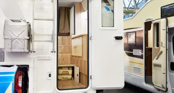 Detalle interior de autocaravana, mostrando un baño portátil y armarios de madera. Ideal para quienes buscan concesionarios de autocaravanas en Alemania.