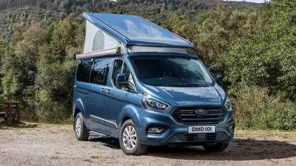 Furgoneta camper azul Westfalia Nugget con techo elevable, lista para una aventura en la naturaleza.