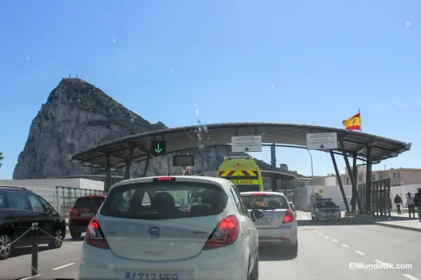 Fila de coches en la frontera de Gibraltar, con el Peñón al fondo. Señales indican dónde dove parcheggiare a Gibilterra.