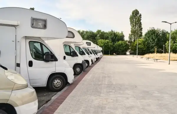 Fila de autocaravanas blancas aparcadas en un área de descanso. Consulta el precio parking caravanas para tu próxima aventura.