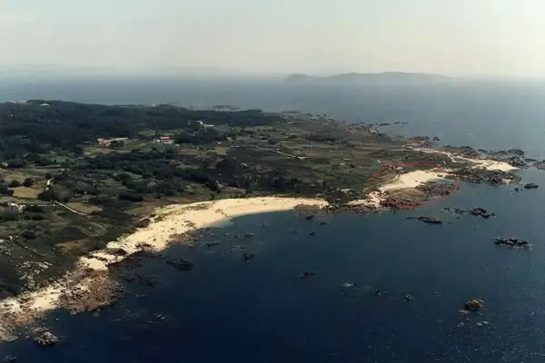 Vista aérea de la playa de Barreiro o Grove, con arena dorada, rocas y el mar azul.