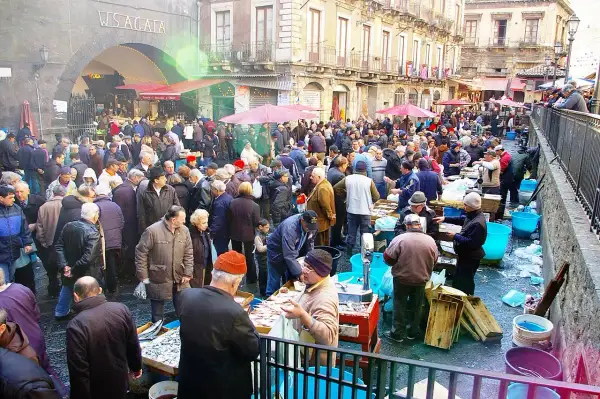 Mercado bullicioso en Palermo, con gente comprando pescado fresco. Un día ajetreado en este lugar, que algunos consideran **palermo peligroso** por su intensidad.
